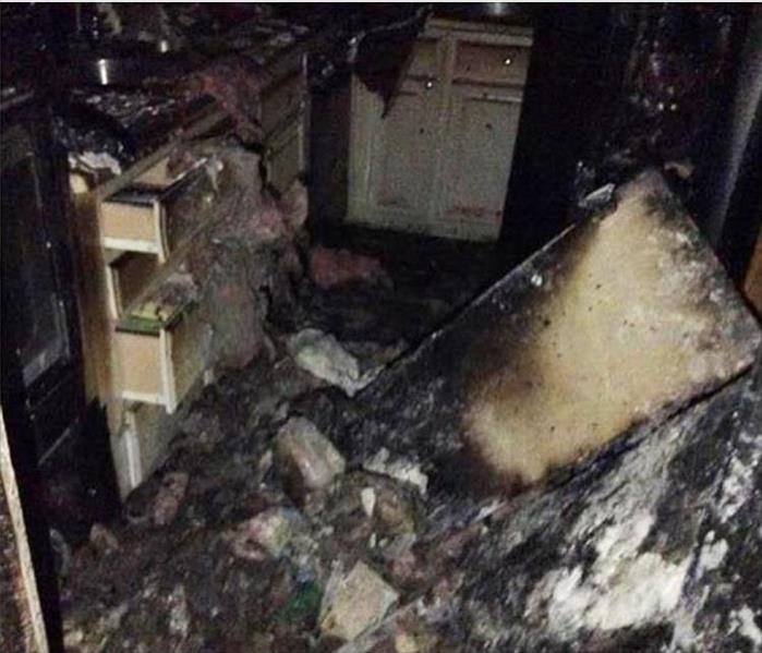 burned and charred debris, cabinets, and ceiling material in a kitchen