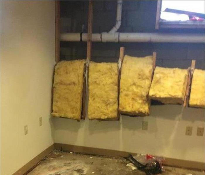 opened wall, folded over batten insulation, exposing pvc plumbing
