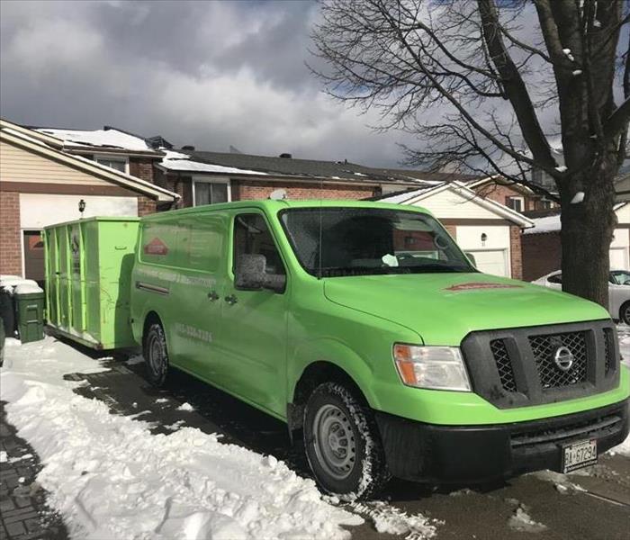 Green truck and trailer parked at house in snow